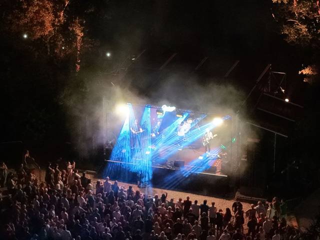 Aerial still of a festival stage at night, lighting rig and crowd from above
